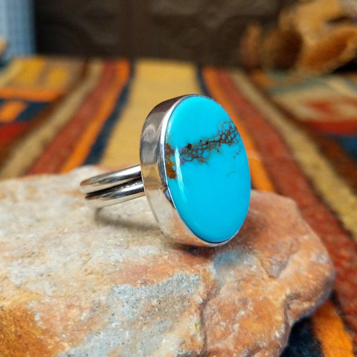 Redskin Turquoise Ring by Everett & Mary Teller featuring a large oval sky-blue turquoise stone with distinctive brown spiderweb matrix, a smooth polished surface, and a simple silver bezel setting; side view.