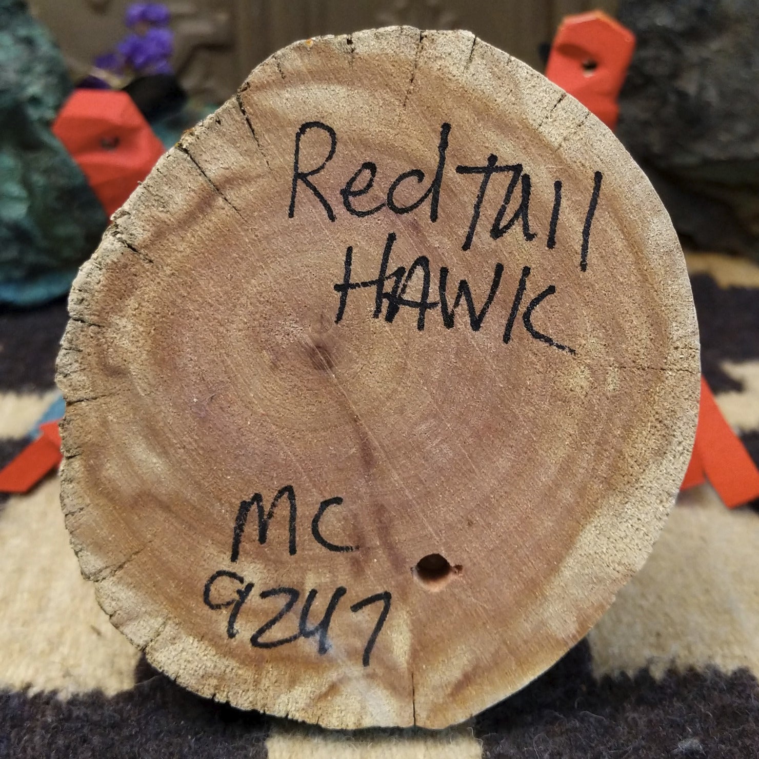 Underside of M. C. redtail hawk kachina doll showing handwritten signature and label on wood base.