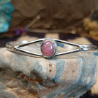 Sterling silver cuff with rhodochrosite set in a round bezel, framed by twisted rope accents.