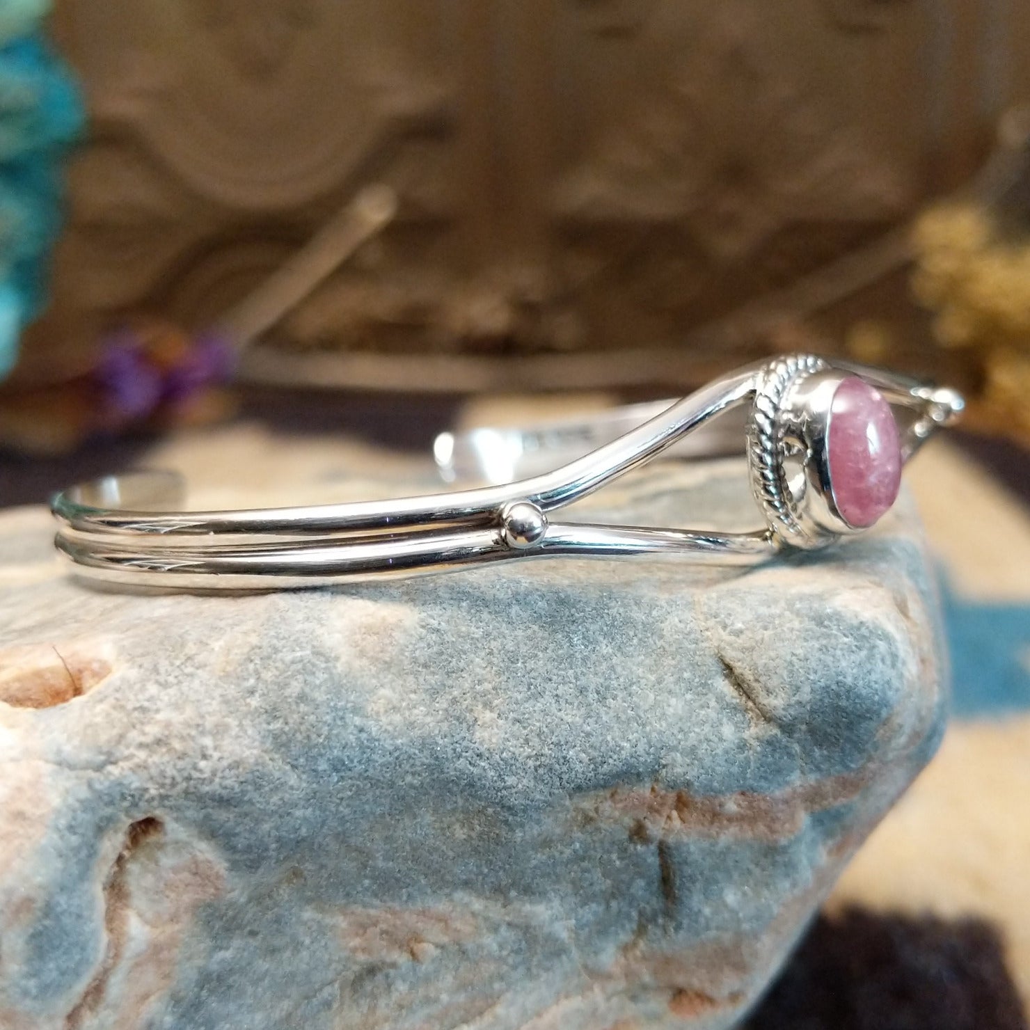 Sterling silver cuff with rhodochrosite set in a round bezel, framed by twisted rope accents.