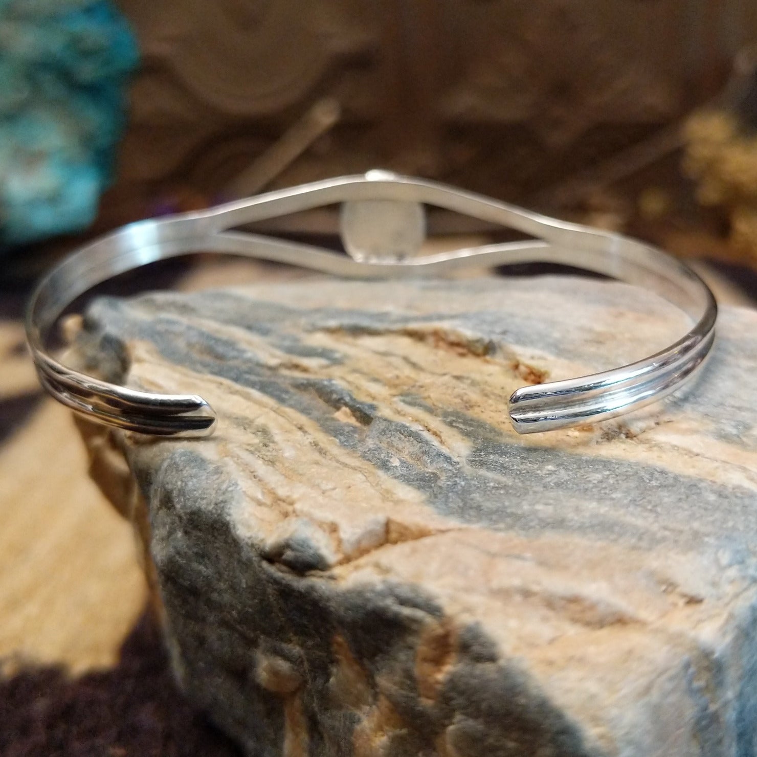 Sterling silver cuff with rhodochrosite set in a round bezel, framed by twisted rope accents.