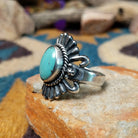 Sterling silver turquoise ring by Raymond Coriz featuring an oval turquoise cabochon, twisted rope bezel, concho-inspired fan design, and intricate Southwestern silverwork; side view.