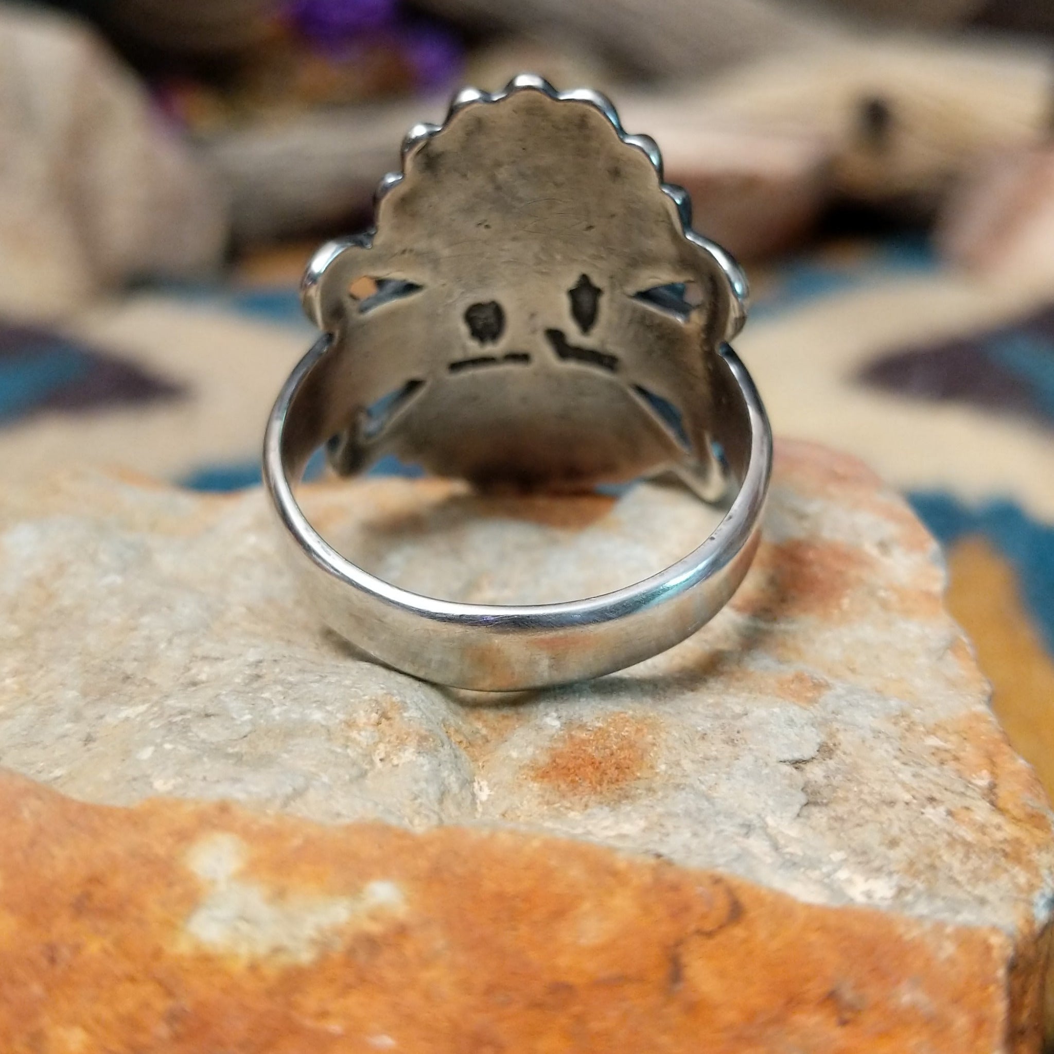 Sterling silver turquoise ring by Raymond Coriz featuring an oval turquoise cabochon, twisted rope bezel, concho-inspired fan design, and intricate Southwestern silverwork; underside view.