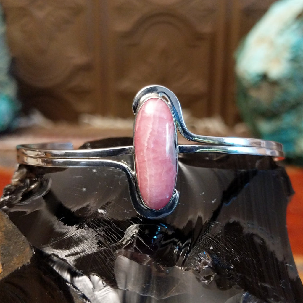 Oval rhodochrosite stone as the centerpiece on the sterling silver bracelet band.