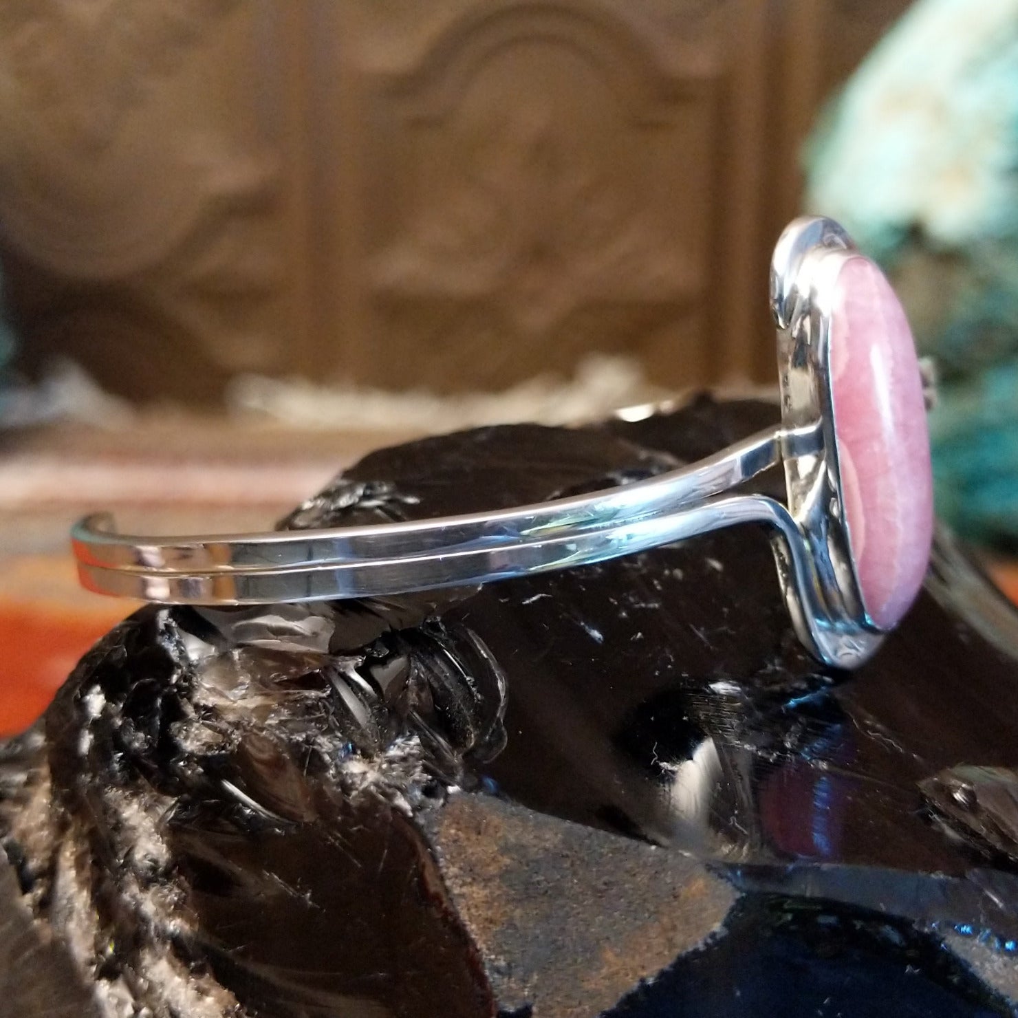 Oval rhodochrosite stone as the centerpiece on the sterling silver bracelet band.
