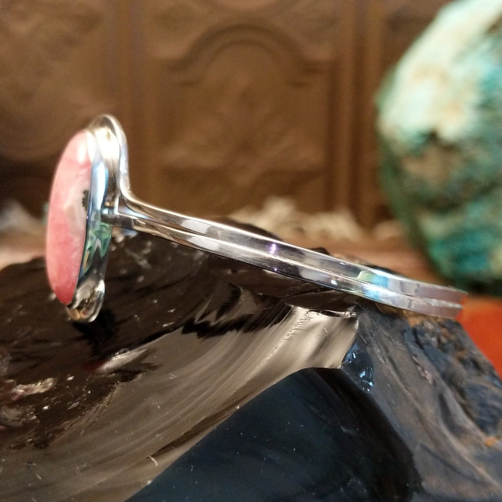 Oval rhodochrosite stone as the centerpiece on the sterling silver bracelet band.