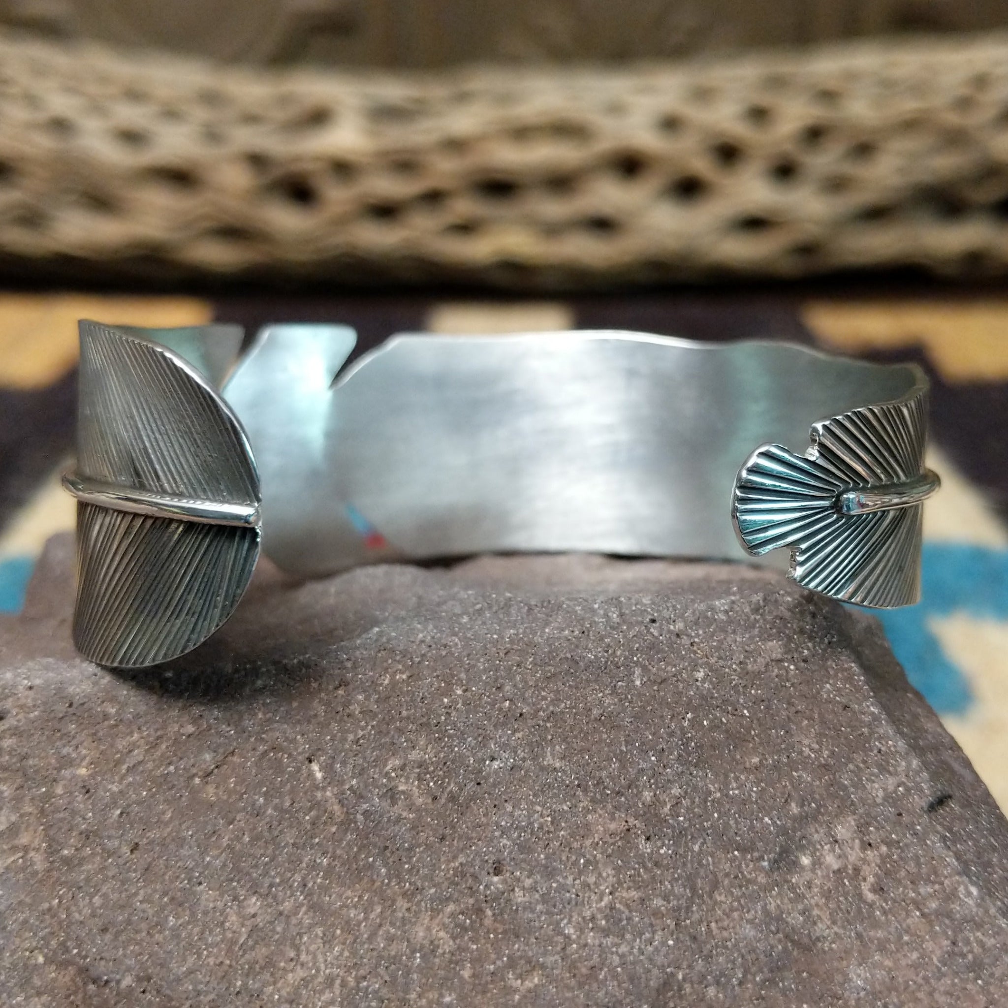 Rippling silver feather cuff by Terry Wood, featuring a handcrafted sterling silver feather design with flowing engraved details and traditional Southwestern-inspired craftsmanship.  Underside view.