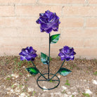 A purple rose bouquet metal art piece with three rich purple roses and green leaves.