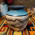 Round horsehair pottery vase by Roger Calhoun with a wide black rim, crackled turquoise-blue shoulder, and smoky black horsehair patterns across a cream-colored body.