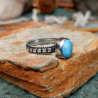 Sterling silver ring by Elgin Tom featuring an oval Golden Hills turquoise stone with natural matrix and a detailed silver band; side view.