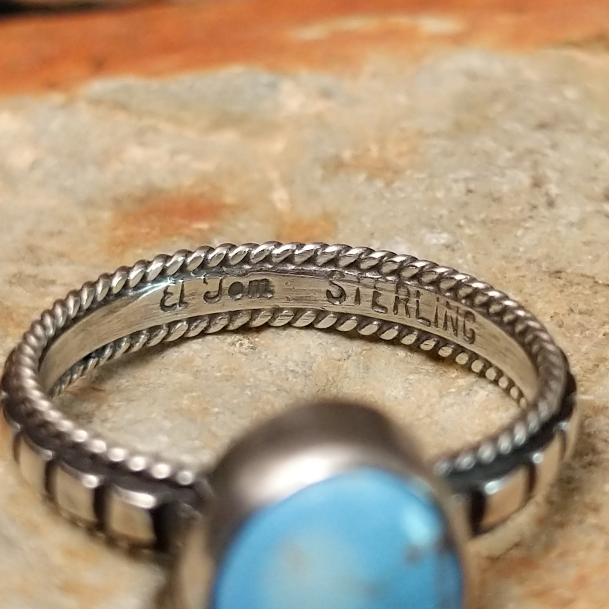 Sterling silver ring by Elgin Tom featuring an oval Golden Hills turquoise stone with natural matrix and a detailed silver band; artisan and Sterling Silver stamp.