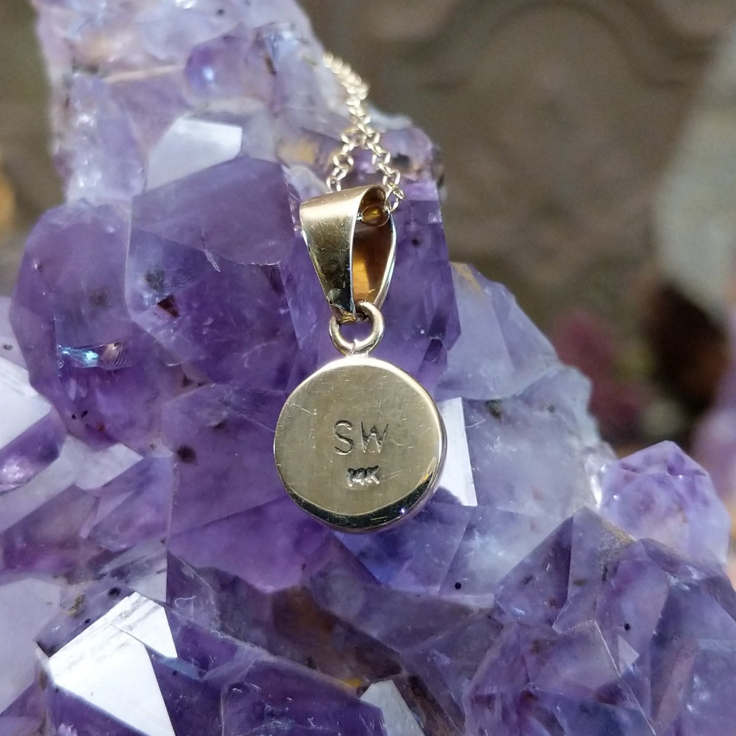Close up of artist's stamped signature and 14K indicating 14 karat gold construction.