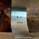 The underside of the cuff showcases the artist's stamp.