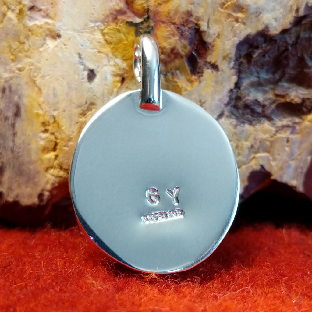 The artisan's initials are stamped on the back of the pendant.