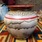 Round horsehair pottery vase by Roger Calhoun with a wide red rim, gold and lavender crackled shoulder, red accent band, and smoky black horsehair markings across a cream-colored body.