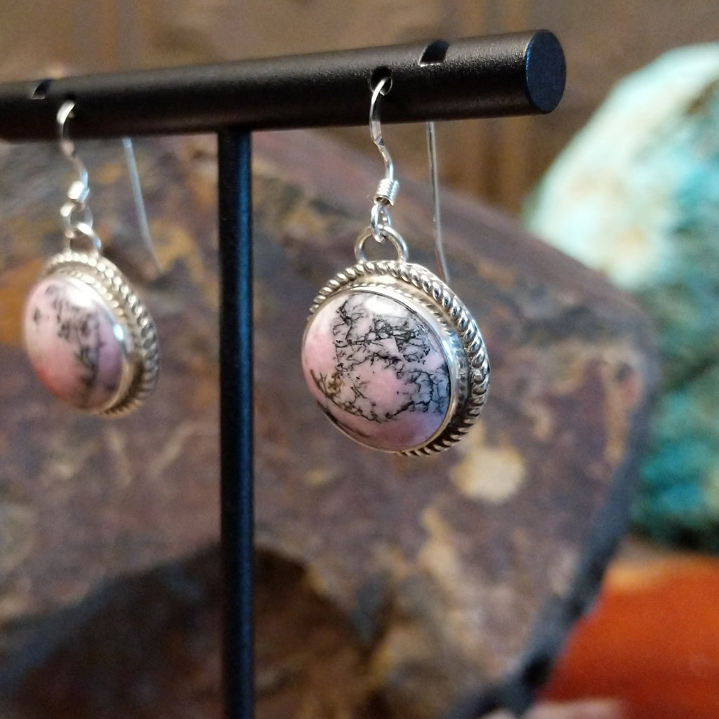 Round rhodochrosite earrings set within twisted rope bezels featuring dark matrix within the stone.