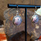 Round rhodochrosite earrings set within twisted rope bezels featuring dark matrix within the stone.