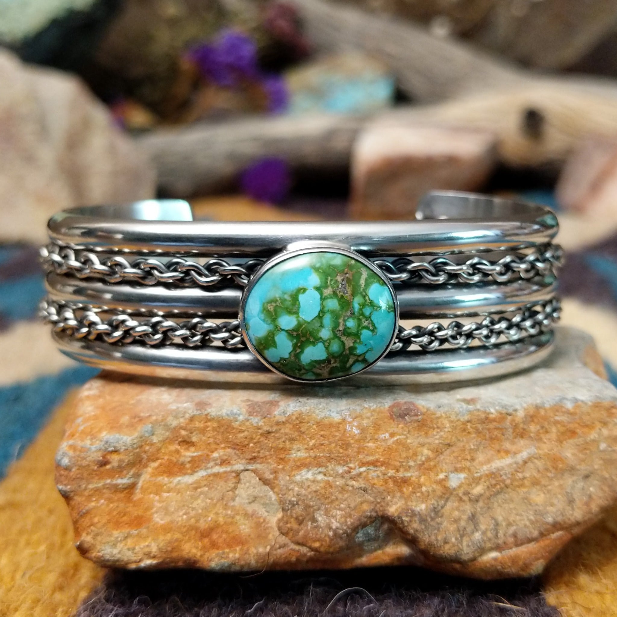 Handcrafted sterling silver cuff by H.R.M. featuring a round Sonoran Gold turquoise cabochon centered between polished silver bands with dual oxidized chain accents.