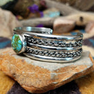 Handcrafted sterling silver cuff by H.R.M. featuring a round Sonoran Gold turquoise cabochon centered between polished silver bands with dual oxidized chain accents; side view.