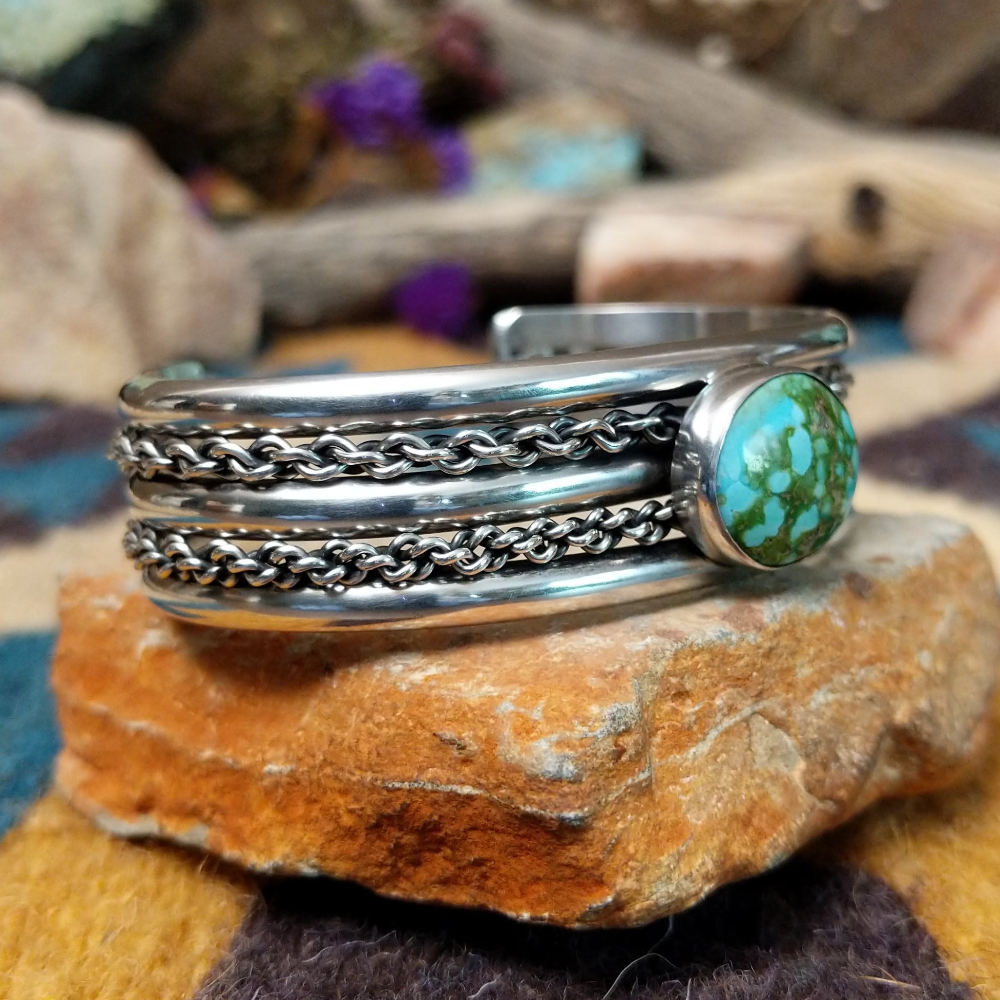 Handcrafted sterling silver cuff by H.R.M. featuring a round Sonoran Gold turquoise cabochon centered between polished silver bands with dual oxidized chain accents; side view.