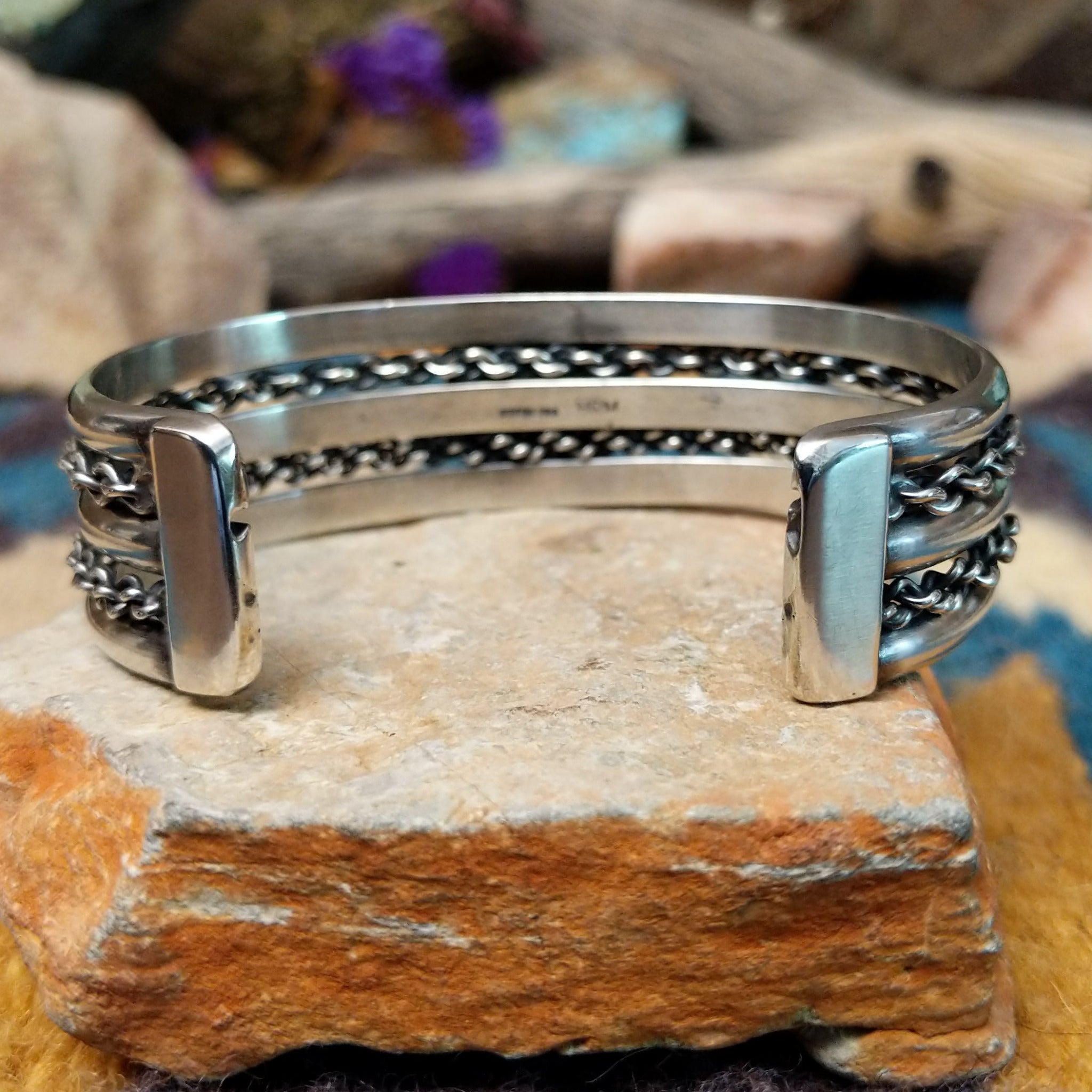 Handcrafted sterling silver cuff by H.R.M. featuring a round Sonoran Gold turquoise cabochon centered between polished silver bands with dual oxidized chain accents; underside view.