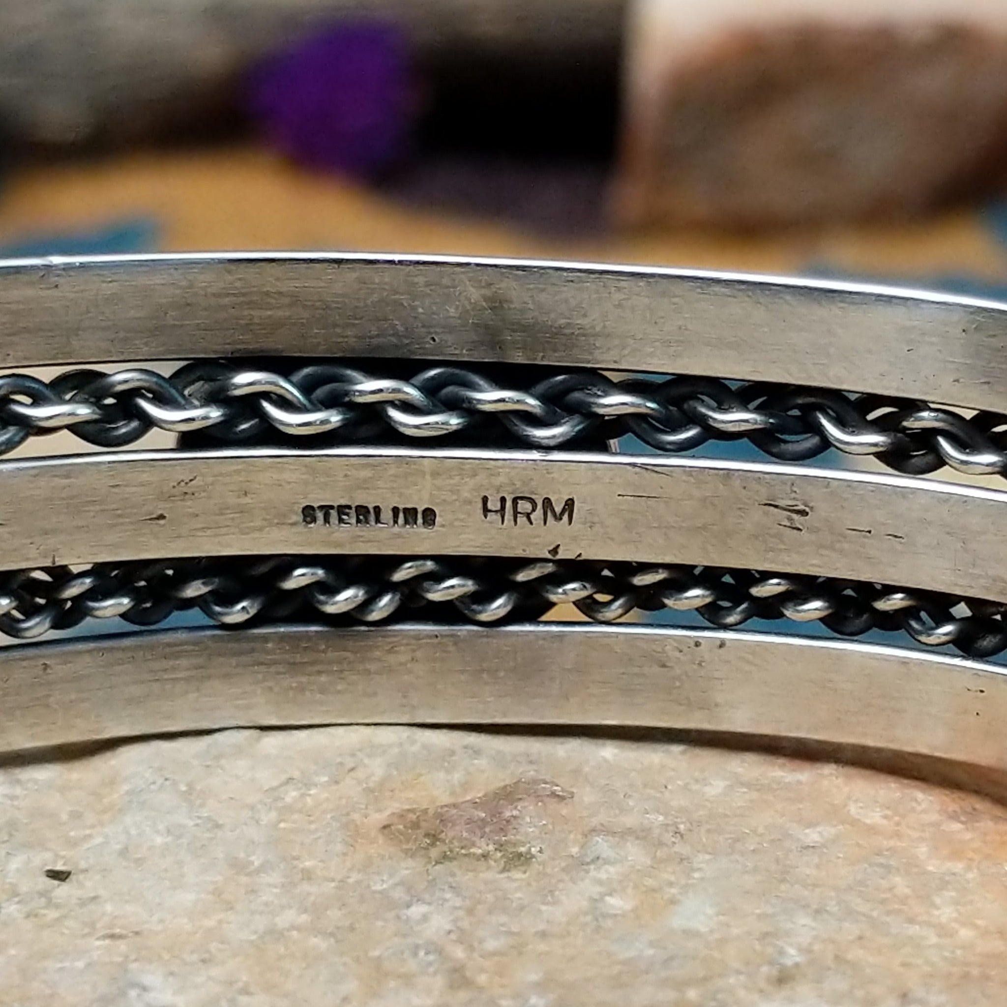 Handcrafted sterling silver cuff by H.R.M. featuring a round Sonoran Gold turquoise cabochon centered between polished silver bands with dual oxidized chain accents; artisan and Sterling Silver stamp.