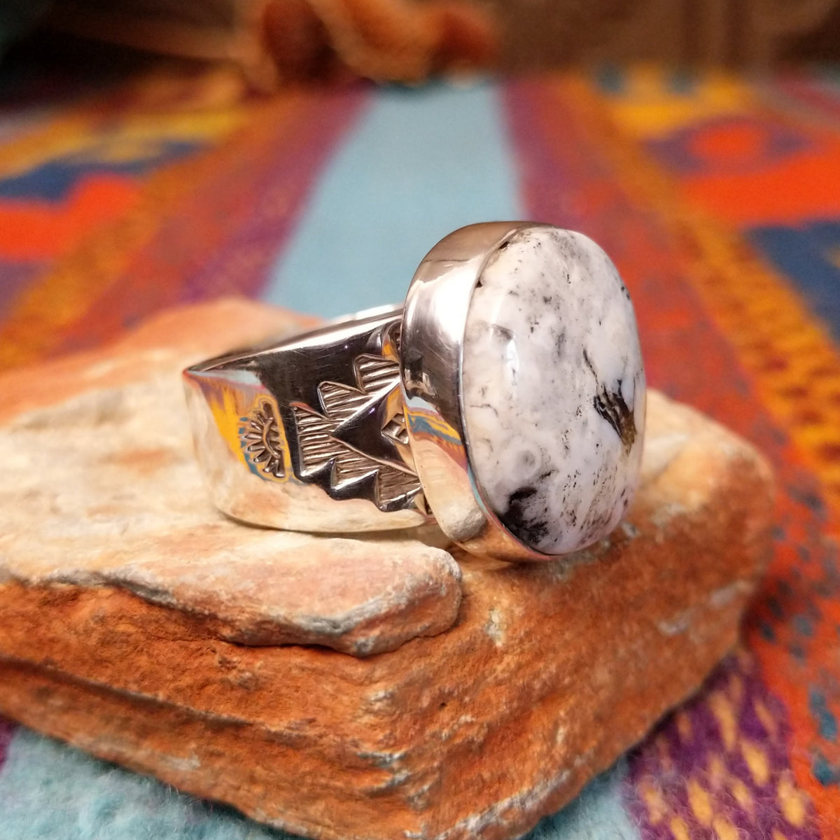 Round White Buffalo Ring by L.P. featuring a large creamy white cabochon with natural black and gray matrix, set in a smooth silver bezel with a substantial detailed silver band; side view.