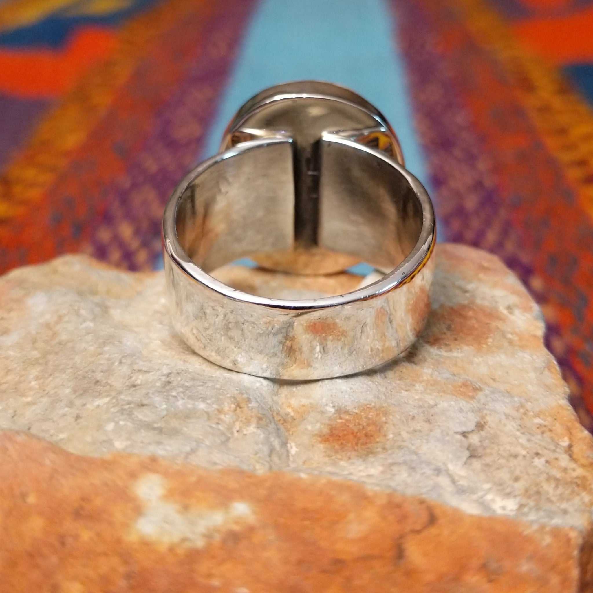 Round White Buffalo Ring by L.P. featuring a large creamy white cabochon with natural black and gray matrix, set in a smooth silver bezel with a substantial detailed silver band; underside view.