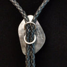 A braided leather bolo tie necklace, displayed on a black velvet mannequin bust. The tie features the artist and Sterling Silver stamp on back.