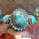 Large sterling silver cuff bracelet with Royston turquoise set in large bezels, framed by stamping and twisted rope designs.
