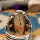 Handcrafted sterling silver ring featuring an elongated oval Royston turquoise cabochon with vivid green tones and golden-brown matrix, set in an ornate oxidized silver bezel with decorative bead accents; artisan and Sterling Silver stamp.