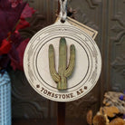 Saguaro Wood Ornament featuring a raised green cactus design, engraved circular wooden frame, “Tombstone, AZ” lettering, and natural twine hanging loop.