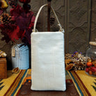 Sandstone Club Bag by Bamboo Trading featuring intricate Southwestern geometric beadwork in ivory, charcoal, slate blue, silver, and peach, with symmetrical diamond patterns, sparkling sequins, and a cream-colored shoulder strap; back side view.