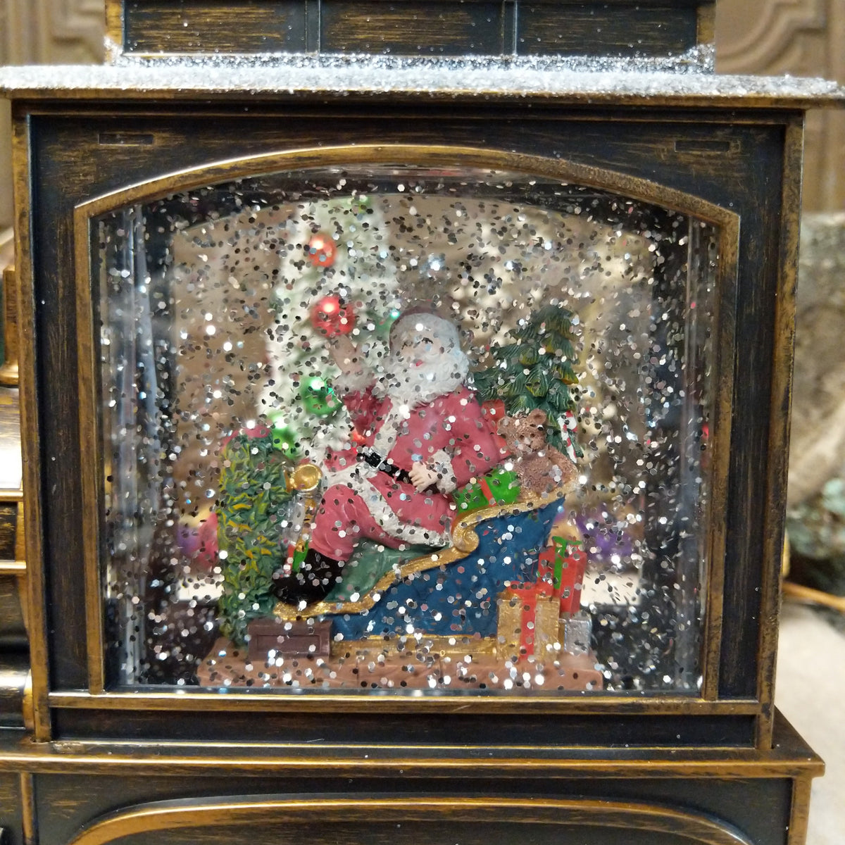 Vintage steam train snow globe with Santa in a sleigh, Christmas trees, presents, teddy bear, lights, and swirling glitter snow.