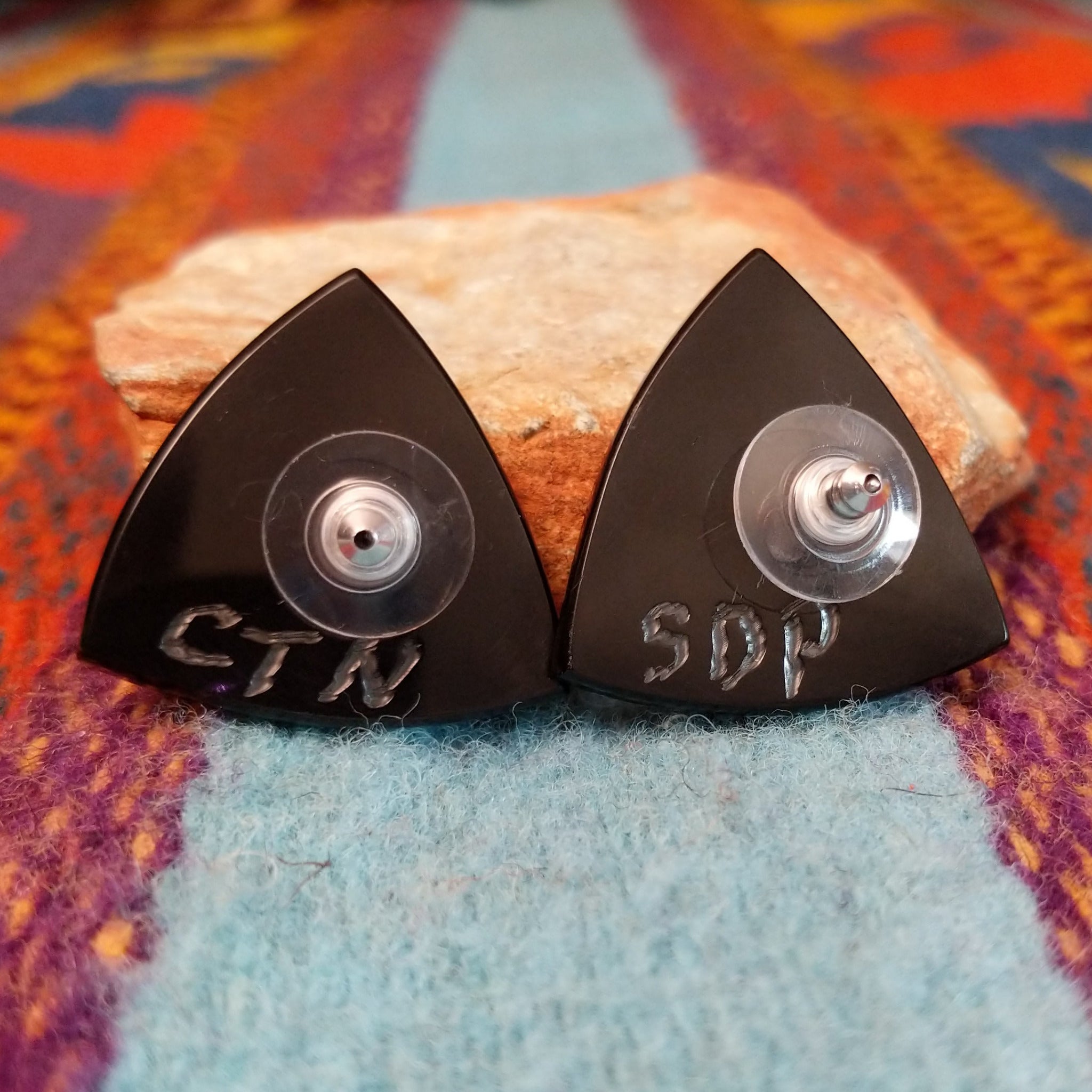 Close up of earring posts and artist's signature