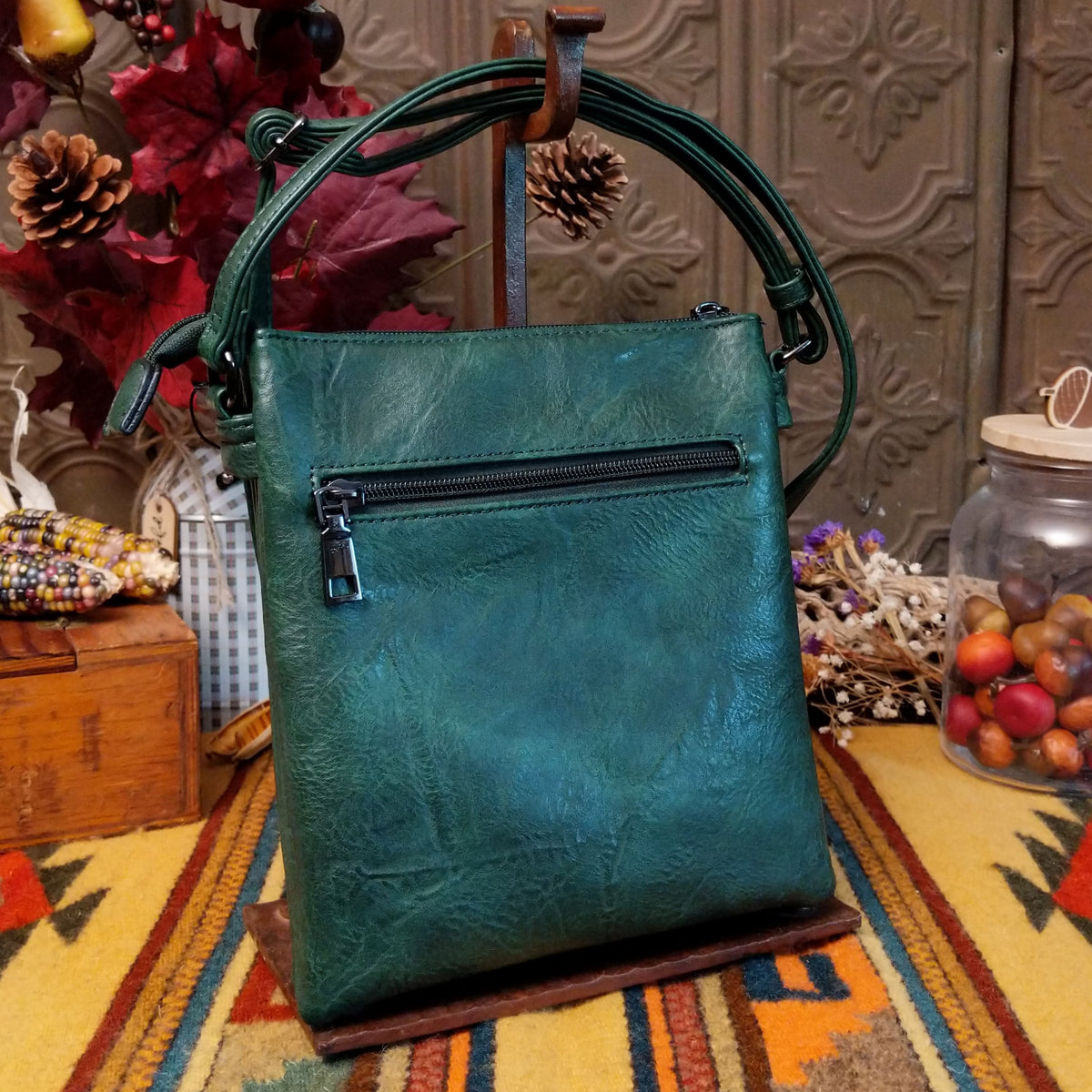 Sara Crossbody Bag by Liz Soto featuring a structured silhouette, embossed botanical front panel, zippered pocket, tassel zipper pull, top zip closure, and adjustable shoulder strap; back side.
