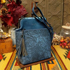 Selena Crossbody Bag by Liz Soto featuring embossed floral detailing, vintage-style kiss-lock frame closure, front zippered pocket, decorative tassel, and adjustable shoulder strap.