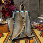 Selena Crossbody Bag by Liz Soto featuring embossed floral detailing, vintage-style kiss-lock frame closure, front zippered pocket, decorative tassel, and adjustable shoulder strap; back view.