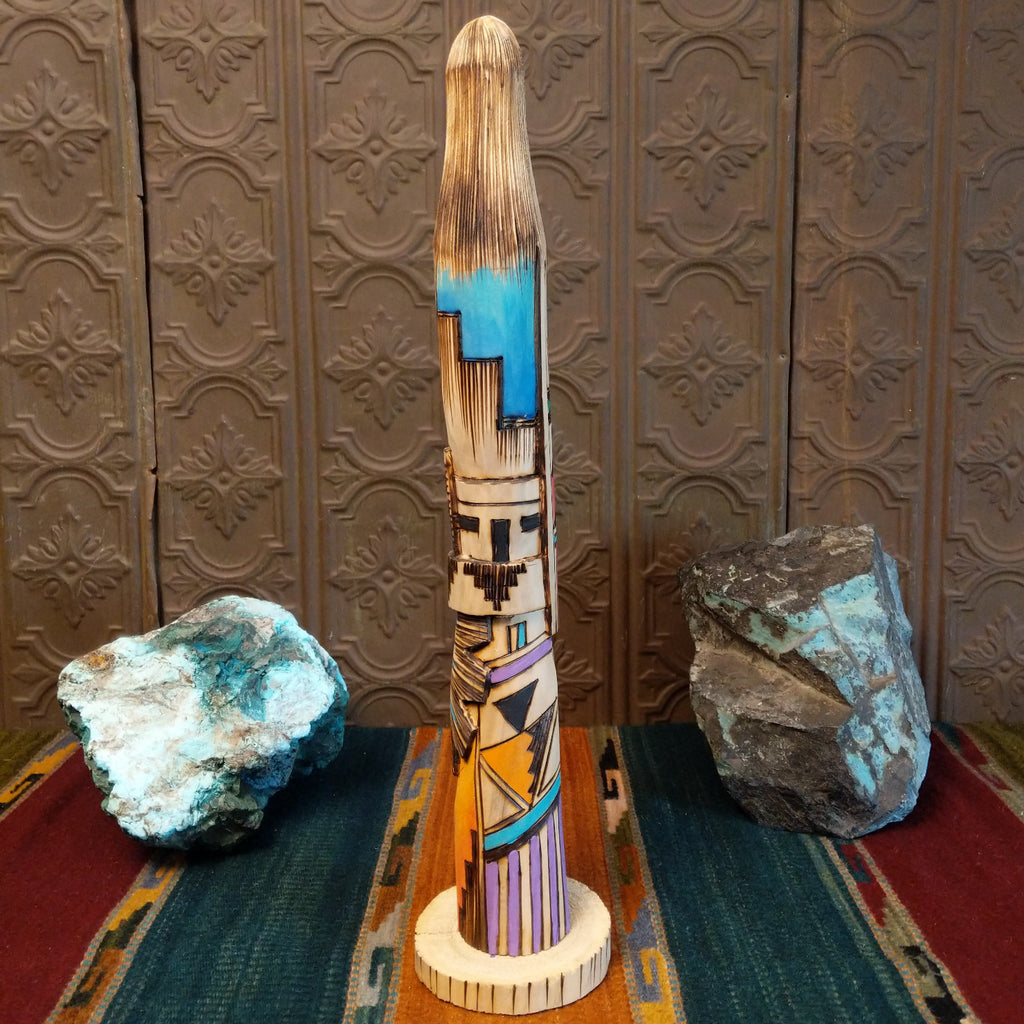 Shalako kachina carved from wood with various, vibrant designs all along it.