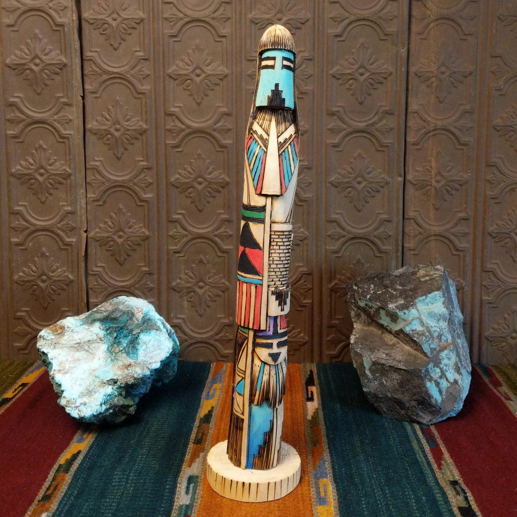 Shalako kachina carved from wood with various, vibrant designs all along it.