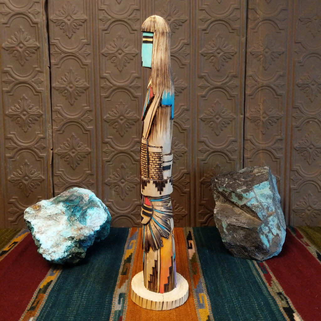 Shalako kachina carved from wood with various, vibrant designs all along it.