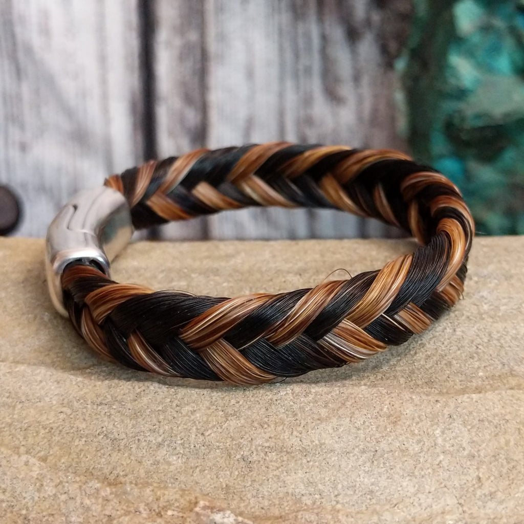 A braided multi-toned horsehair bracelet in black, brown, and tan, secured with a magnetic clasp.