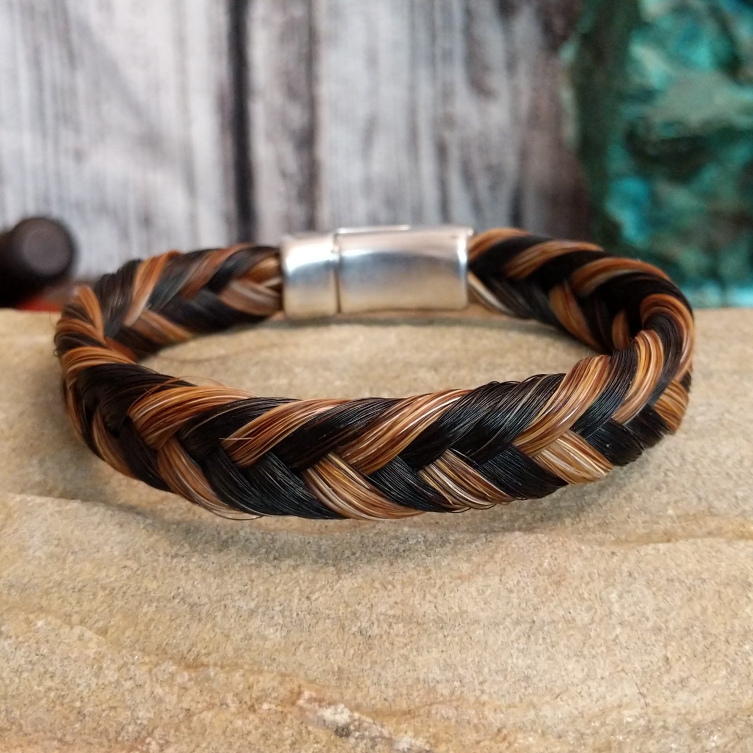 A braided multi-toned horsehair bracelet in black, brown, and tan, secured with a magnetic clasp.