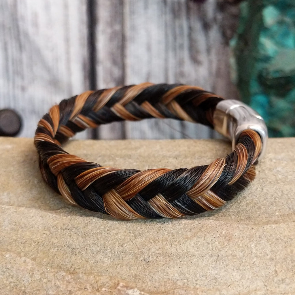 A braided multi-toned horsehair bracelet in black, brown, and tan, secured with a magnetic clasp.