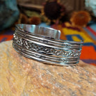 Silver cuff by Sunshine Reeves with two stamped arrows and central repeating diamond pattern.
