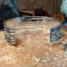 Silver cuff by Sunshine Reeves with two stamped arrows and central repeating diamond pattern.