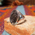 Silver Bison Ring by Calvin Peterson featuring a raised bison motif with geometric detailing, darkened recessed accents, and a polished Sterling Silver oval face and band; side view.