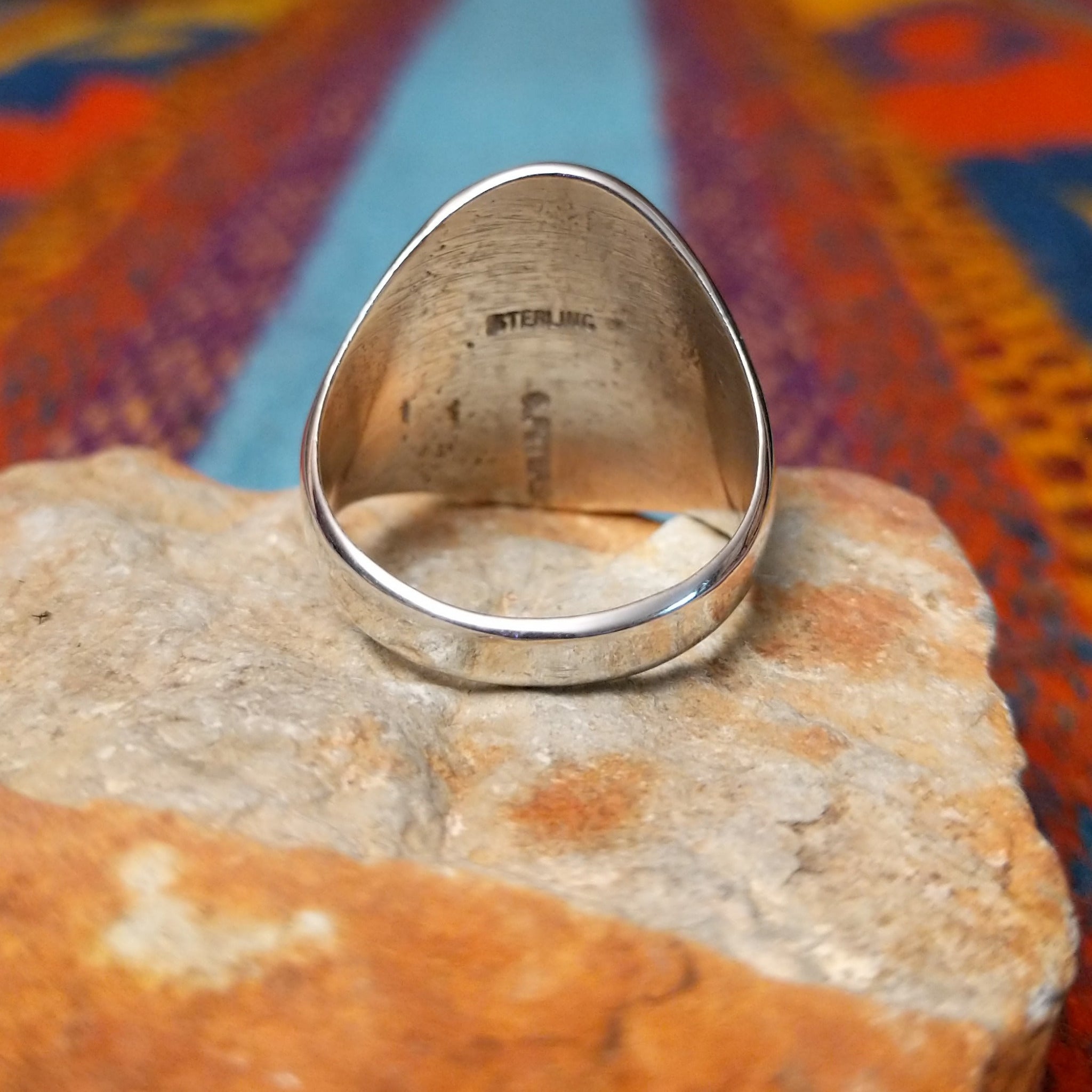 Silver Bison Ring by Calvin Peterson featuring a raised bison motif with geometric detailing, darkened recessed accents, and a polished Sterling Silver oval face and band; underside view.
