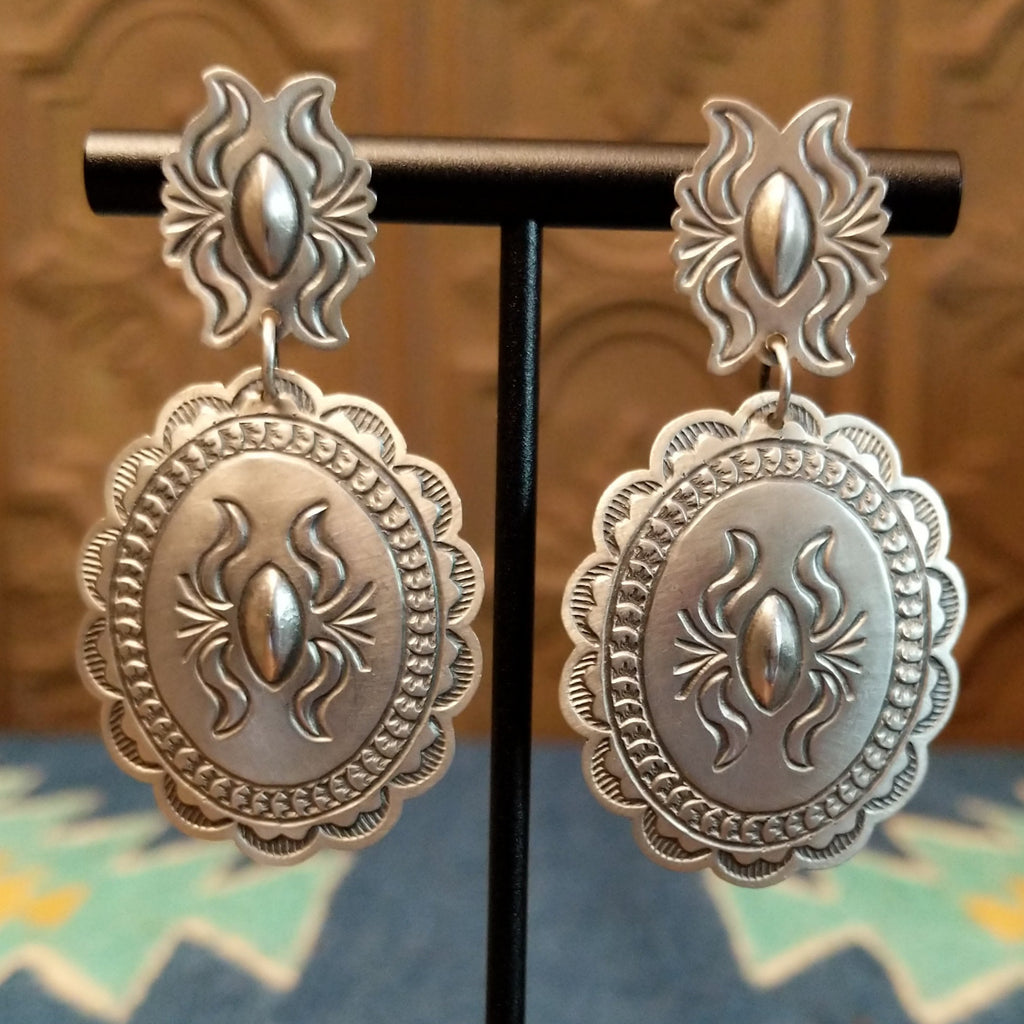 Silver concho earrings with intricate details.