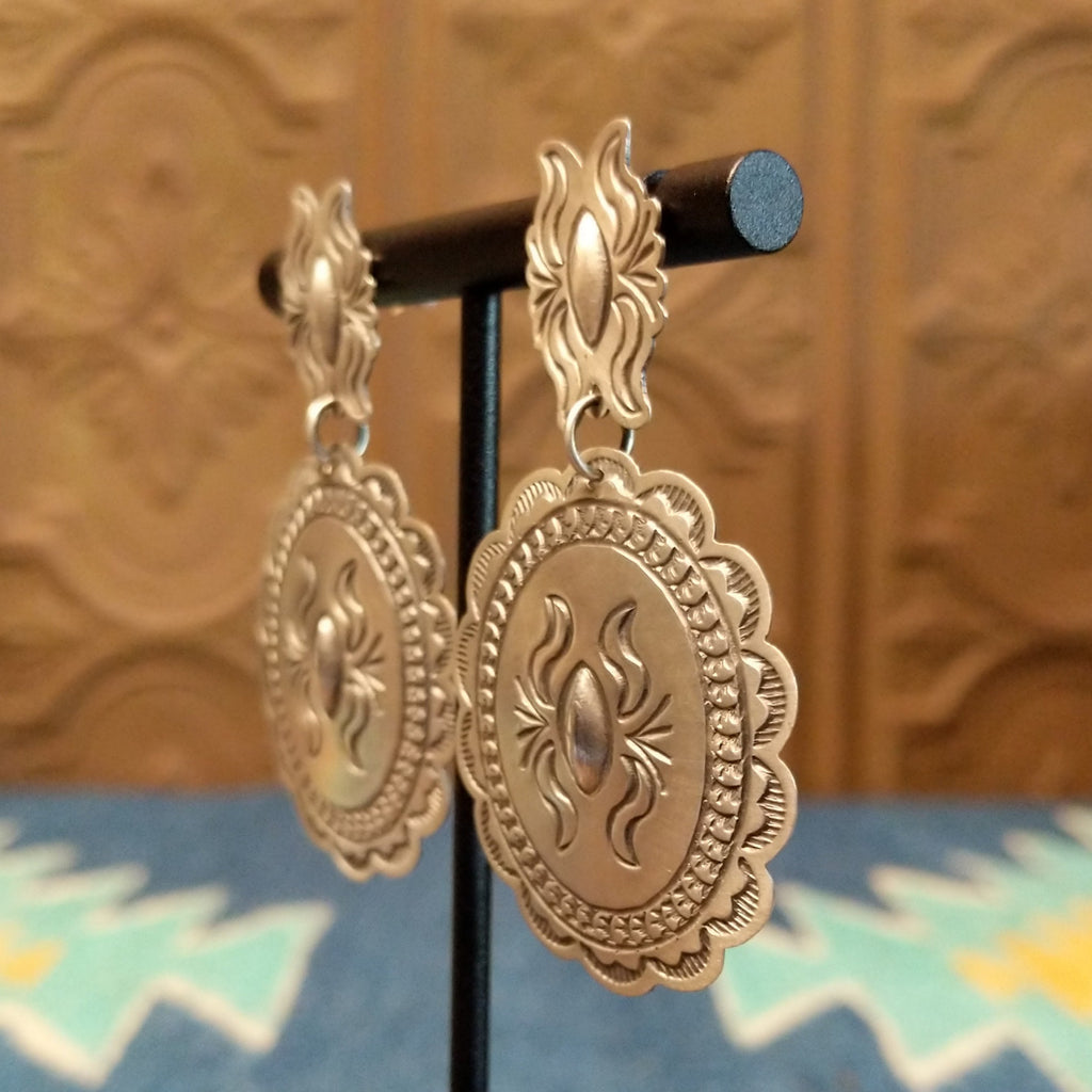 Silver concho earrings with intricate details.